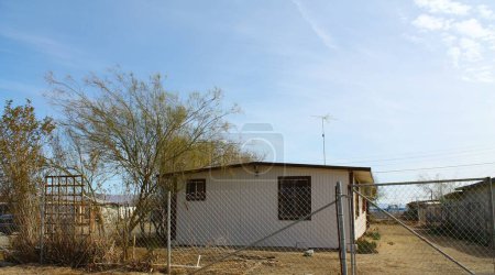 Téléchargez les photos : Petite maison modulaire avec clôture à chaînette dans un quartier désertique - en image libre de droit