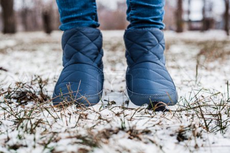 Photo for Winter puffy boots on female legs in winter on snow - Royalty Free Image