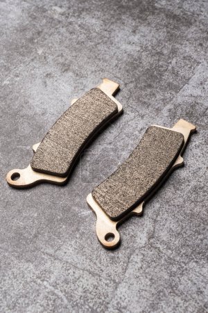 Téléchargez les photos : Brand new metallic motorcycle brake pads on a gray surface - en image libre de droit