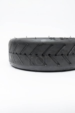 Téléchargez les photos : Nouveau pneu pour scooter électrique couché sur une surface blanche - en image libre de droit