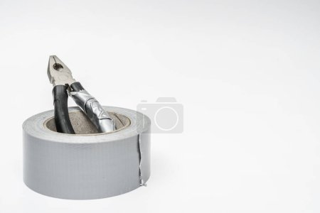 Photo for A used pliers inside a roll of gray adhesive tape - Royalty Free Image