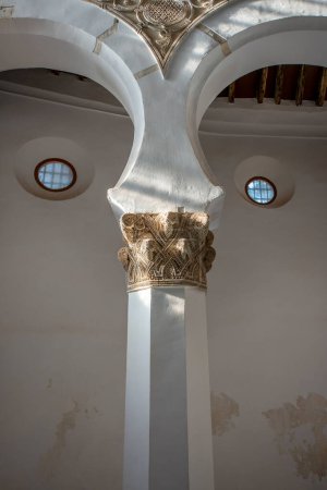 Foto de Un pilar con un capitel tallado bajo algunos arcos en un templo hebreo - Imagen libre de derechos