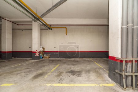An empty parking space in the basement of an urban residential building tote bag #668641852