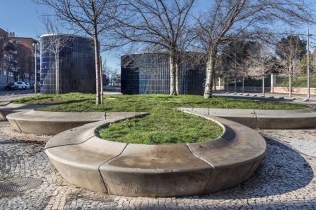 Téléchargez les photos : Un parc urbain avec des sièges circulaires en pierre et des jardins avec des arbres au sommet. - en image libre de droit
