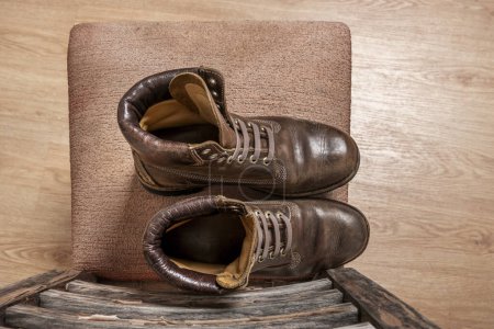Foto de Una bota de senderismo de cuero marrón con costuras triples en un asiento viejo visto desde la parte superior - Imagen libre de derechos