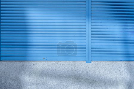 Blue metal shutters with security closure on the granite facade in a premises on the ground floor of an office building