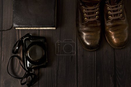 une composition avec des bottes en cuir, un livre vintage et un étui caméra obscura