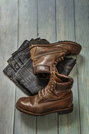Brown leather mountain boots with folded denim pants