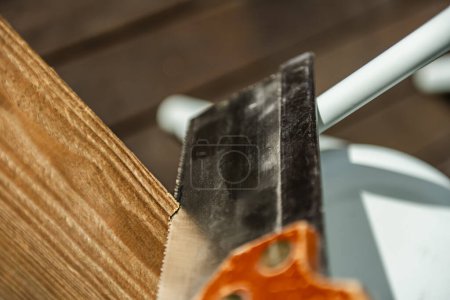A metal saw cutting a piece of wood