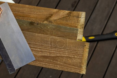 The teeth on the spine of a manual carpentry saw on some wooden boards
