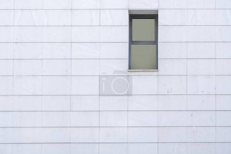 Foto de Pequeña ventana rectangular de aluminio gris en una pared de azulejos blancos - Imagen libre de derechos