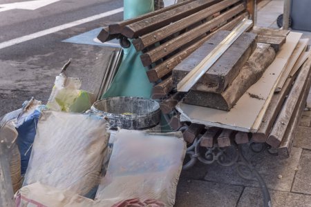 Téléchargez les photos : Un tas de matériaux de construction sur un banc métallique et des lattes en bois au milieu de la rue - en image libre de droit