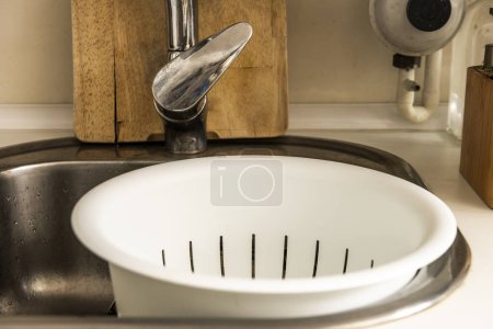 a white plastic strainer in a kitchen sink with a white countertop