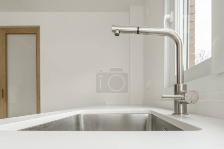 Chrome faucet on a kitchen counter with a single bowl sink
