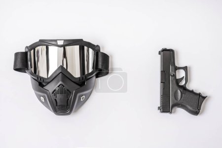 A black airsoft mask along with a handgun