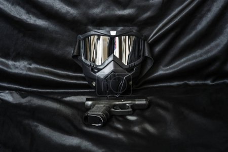 A black airsoft mask along with a handgun