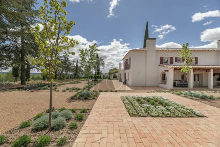 Jardines recién plantados con suelos de terracota y grava en el patio de una casa de campo andaluza