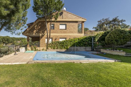 Téléchargez les photos : Une maison de campagne avec façades en brique, une piscine couverte et de l'herbe dans le jardin - en image libre de droit