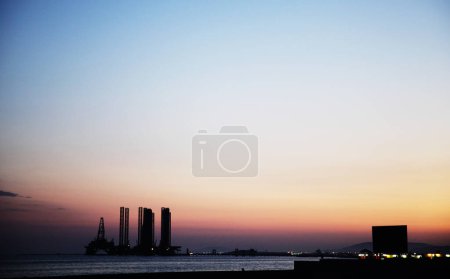 Photo for Silhouette of bridge connected offshore oil production platforms at oil field during sunset - Royalty Free Image