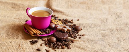 Red cup and saucer with coffee and coffee beans on a brown rag background