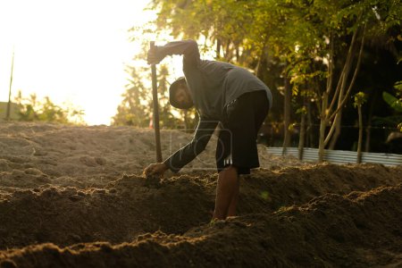Foto de Los agricultores usan azadas mientras cultivan la tierra mientras trabajan en plantaciones - Imagen libre de derechos