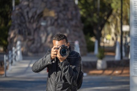 Téléchargez les photos : Photojournaliste latino prenant une photo avec son appareil photo. - en image libre de droit