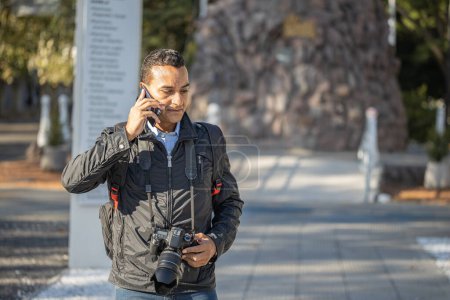 Téléchargez les photos : Photographe travaillant dans la rue et parlant avec son téléphone portable avec de l'espace de copie. - en image libre de droit