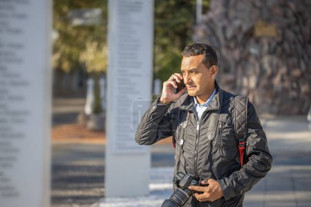Téléchargez les photos : Photographe travaillant dans la rue et parlant avec son téléphone portable. - en image libre de droit