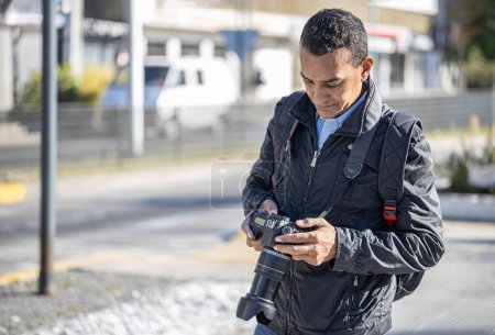 Téléchargez les photos : Photographe revoyant les photos sur son appareil photo dans la rue. - en image libre de droit