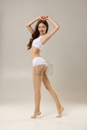Téléchargez les photos : Feeling beautiful. Woman with natural slim tanned body in underwear plays with hair. Healthy lifestyle, low subcutaneous fat, fitness, sport, dieting, plastic surgery or aesthetic cosmetology concept - en image libre de droit