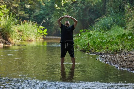 Photo for A man practices qigong and taijiquan while standing in a river in the jungle. High quality photo - Royalty Free Image