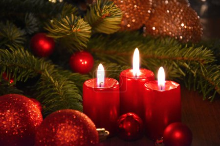 Schöne Weihnachtsdekoration mit brennenden roten Kerzen und Tannenzweigen. Brennende Kerzen und rote Weihnachtskugeln Stillleben Archivfoto. Weihnachtskerze beleuchtet Hintergrundbilder