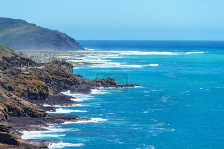 Eine malerische Szene von einer Klippe am Meer, mit Wellen, die sanft auf die Küste krachen, unter einem weiten Himmel