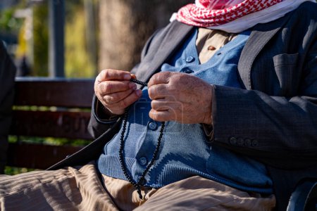 Close up Arab senior man hands holding prayer beads.