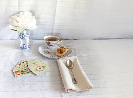 Die perfekte Bridge-Kartenhand mit einer Tasse Tee und Keksen.