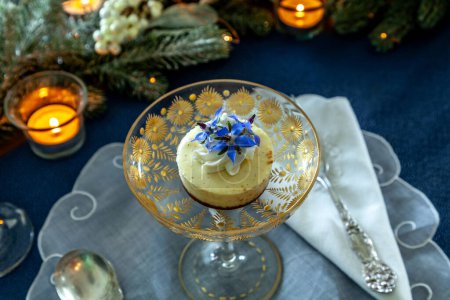 Foto de Postre de pastel de queso y crema batida con polvo de oro en un plato de cristal de lujo con grabado en oro. - Imagen libre de derechos