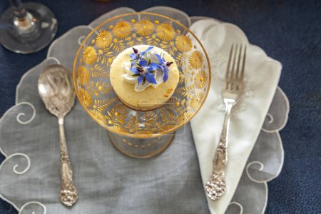 Foto de Postre de pastel de queso y crema batida con polvo de oro en un plato de cristal de lujo con grabado en oro. - Imagen libre de derechos