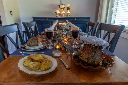 Holiday table with a rack of lamb, steamed artichoke, potatoes and on a bone China plate with candles and holiday decor.