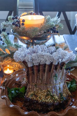 Rack of lamb on a holiday table with steamed artichoke, potatoes and on a bone China plate with candles and holiday decor.