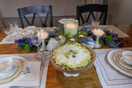 Key lime Cheesecake on an antique cake stand on a table set with candles and flowers.