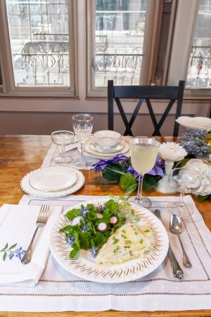 Kabeljau und frühlingshafter grüner Salat auf feinem China mit einem zu Ostern dekorierten Tisch.