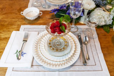 Fresh raspberries in a compote of gold and crystal on a place setting on an Easter table.