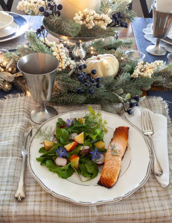 Foto de Ensalada de verduras ecológicas con flores de borraja púrpura, rúcula, rábano y salmón en un plato fino de China con cubiertos elegantes. - Imagen libre de derechos