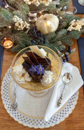 Dessert en mousse au chocolat et crème fouettée à la poussière d'or sur un plat en cristal de fantaisie avec gravure sur or.