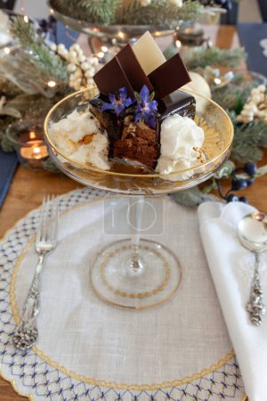 Dessert en mousse au chocolat et crème fouettée à la poussière d'or sur un plat en cristal de fantaisie avec gravure sur or.