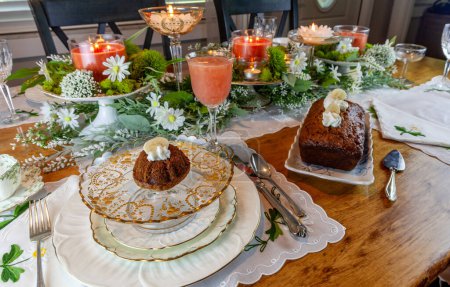 Banana bread with whipped cream served on fine China plates and crystal with gold inlay on a formal table setting.