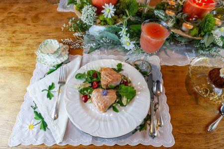 Foto de Corazones de salmón en una ensalada verde de primavera servida en platos finos de China y cristal con incrustaciones de oro en una mesa formal. - Imagen libre de derechos