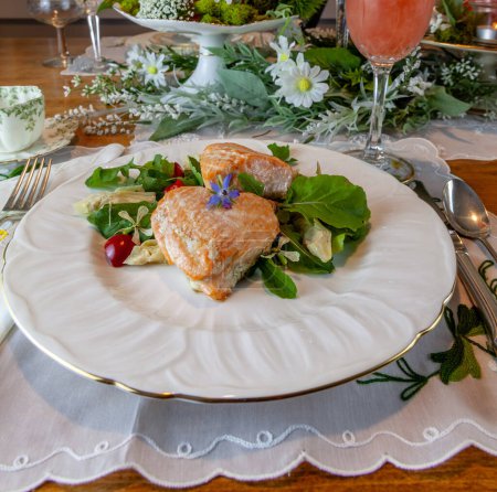 Téléchargez les photos : Coeurs de saumon sur une salade verte printanière servie sur de fines assiettes de Chine et du cristal avec incrustation d'or sur une table formelle. - en image libre de droit