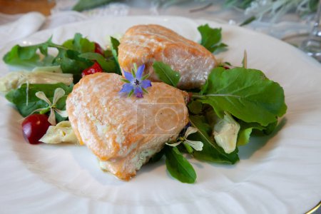 Foto de Corazones de salmón en una ensalada verde de primavera servida en platos finos de China y cristal con incrustaciones de oro en una mesa formal. - Imagen libre de derechos