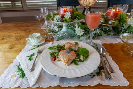 Corazones de salmón en una ensalada verde de primavera servida en platos finos de China y cristal con incrustaciones de oro en una mesa formal.
